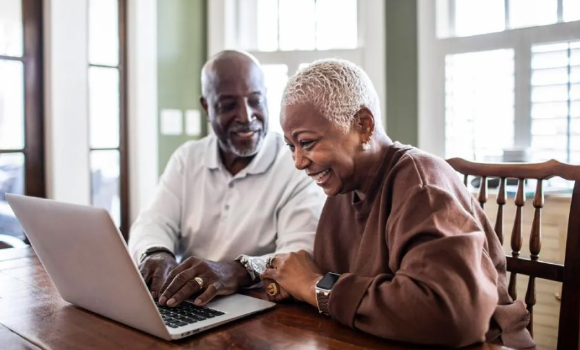 husband and wife looking at life insurance policies on a laptop